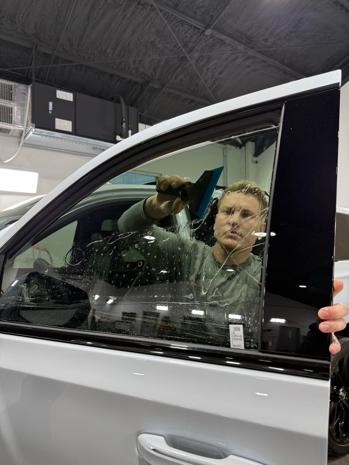 Professional window tinting action shot — technician applying tint film by Auto Trim Design