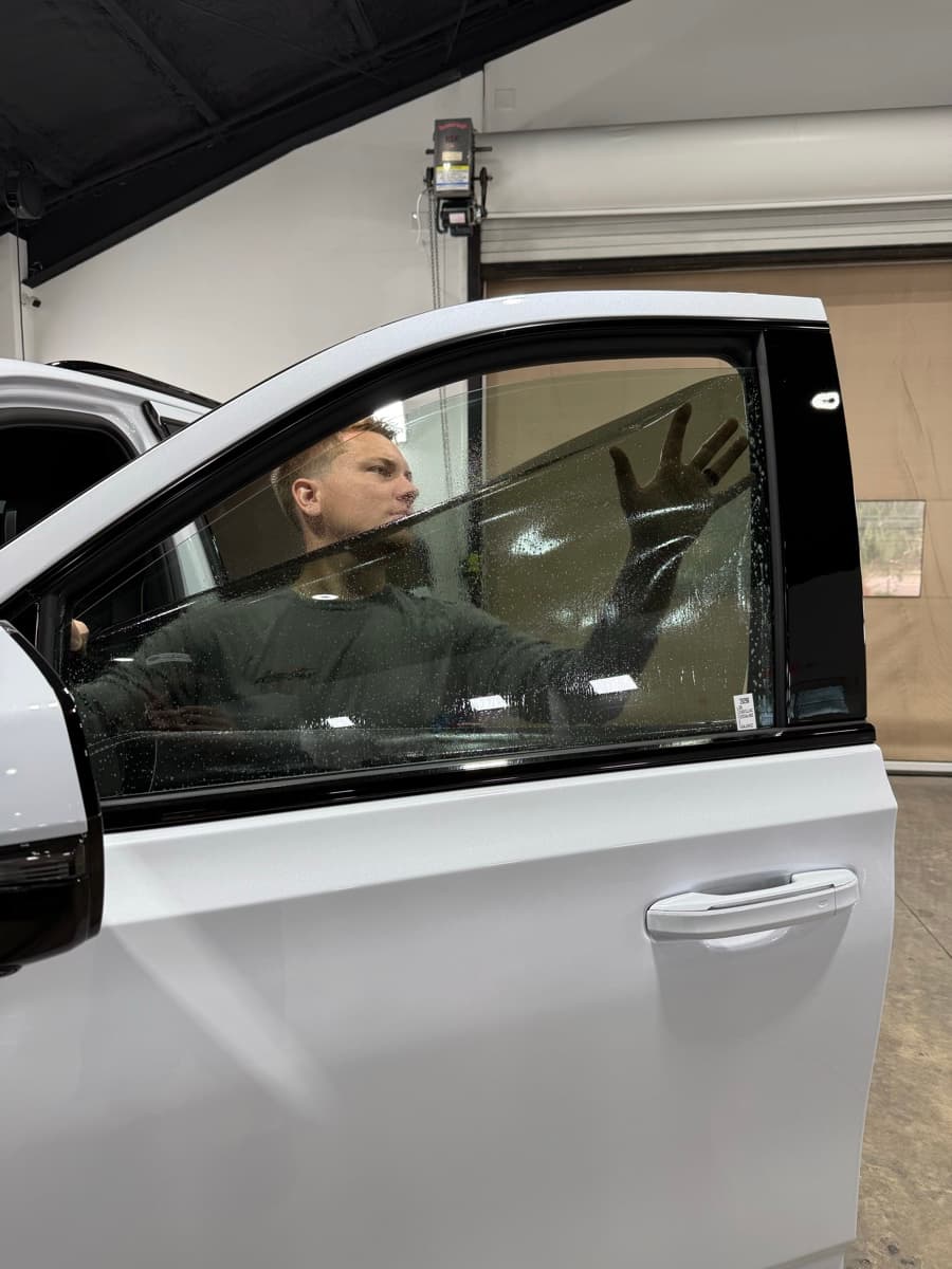 Professional window tinting action shot — technician applying tint film by Auto Trim Design