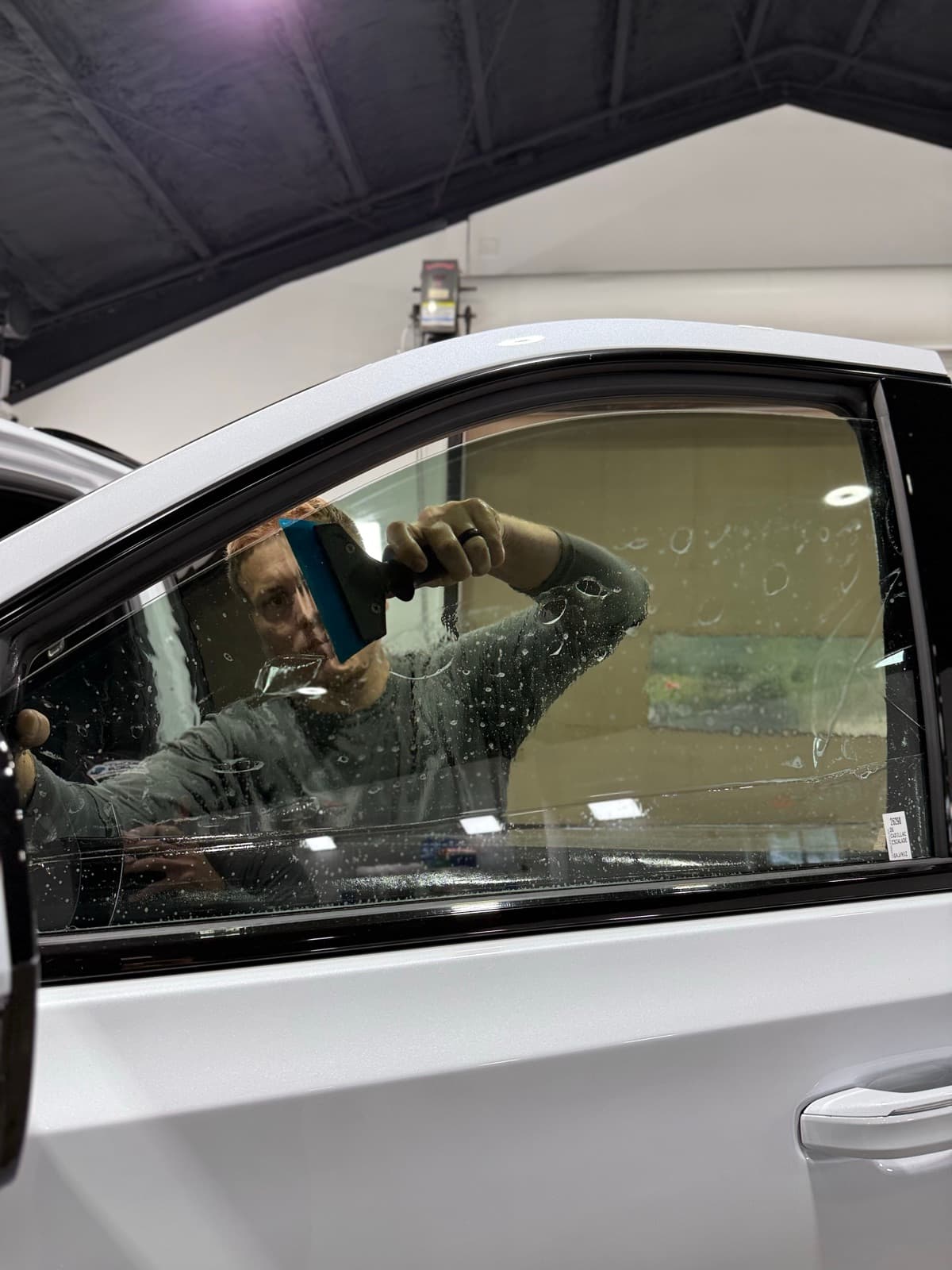 Professional window tinting action shot — technician applying tint film by Auto Trim Design